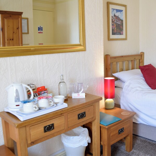 A hotel room with a wooden desk, a bed, a nightstand, a lamp, and a framed picture on the wall. - Bewdley Hill House (Kidderminster)
