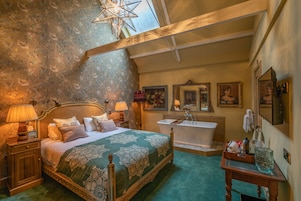 A bedroom with a large bed, a vanity with a mirror, a bathtub, and a star-shaped light fixture.