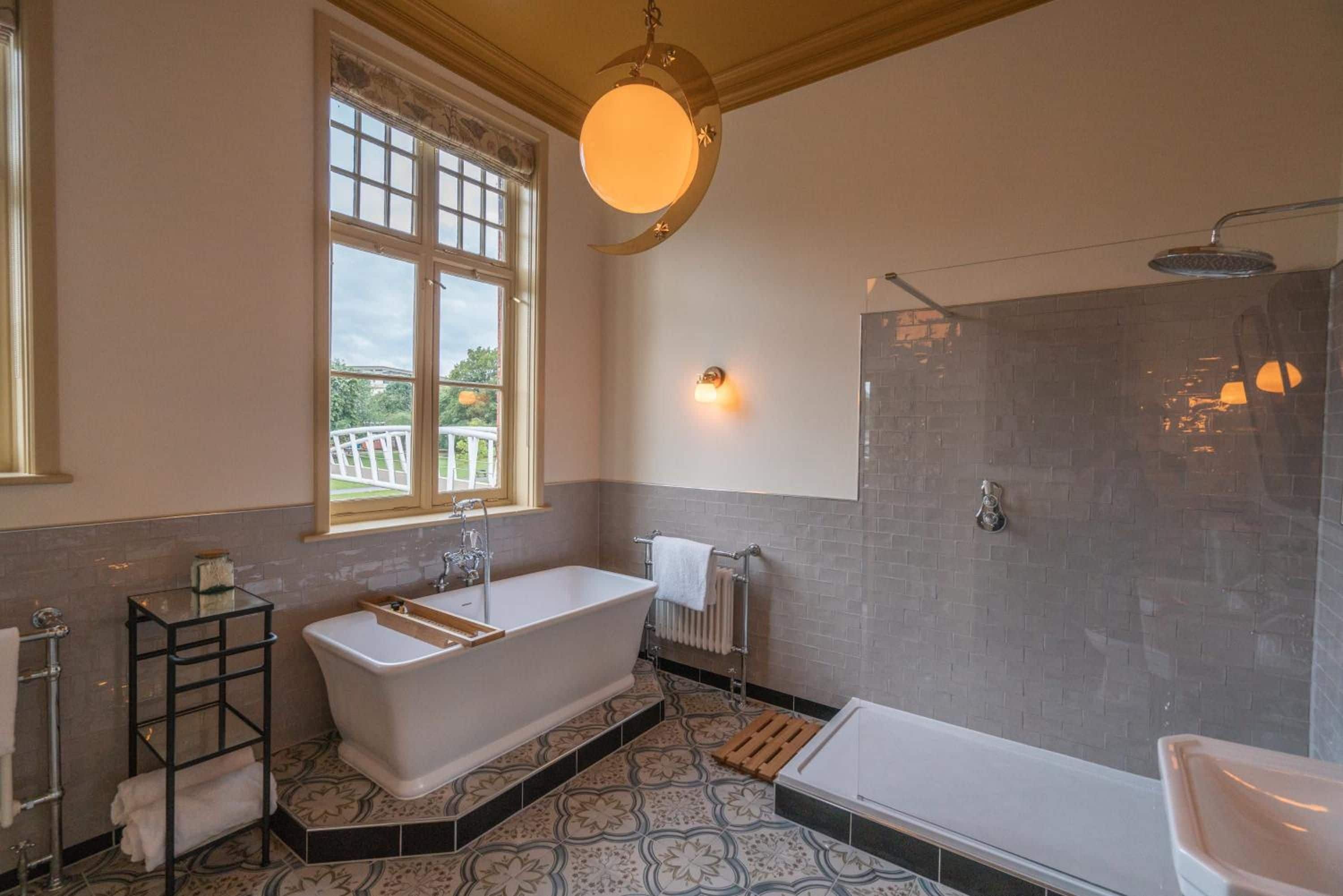 Un baño con una bañera independiente, zona de ducha y ventana que proporciona luz natural.