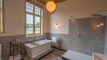 Un baño con una bañera independiente, zona de ducha y ventana que proporciona luz natural.