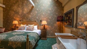 Une chambre à coucher avec un grand lit, deux tables de chevet, une commode, un miroir fixé au mur et une baignoire.