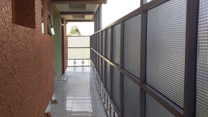 A narrow corridor with a textured wall on one side and a metal mesh fence on the other. - Senevin Gardens Hotel (Kabwohe)