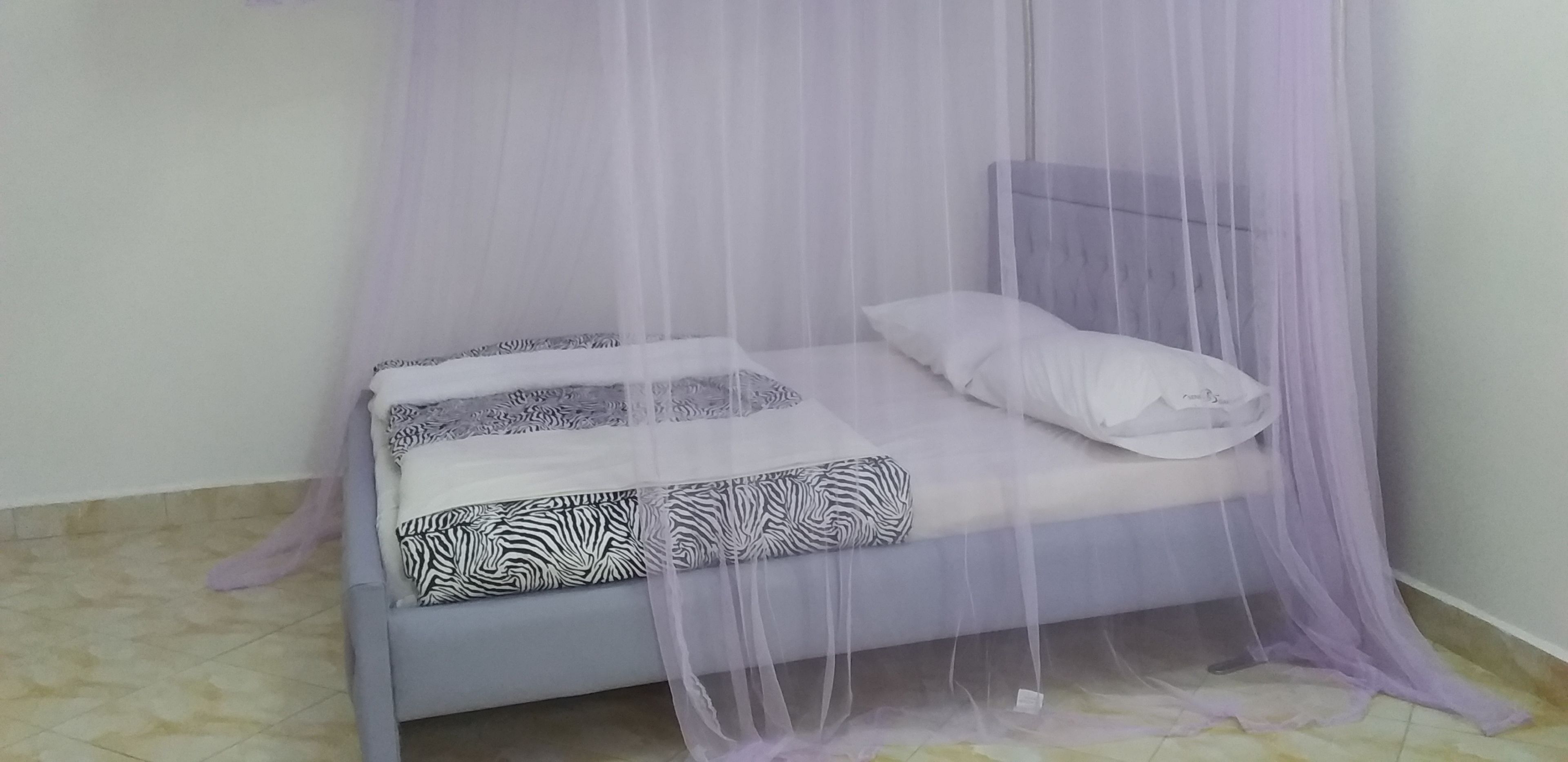 A bed with a canopy, patterned pillows, and a headboard.