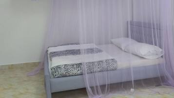 A bed with a canopy, patterned pillows, and a headboard.