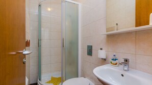 Een badkamer met een douche met glazen wand, een toilet en een wastafel met spiegel erboven.