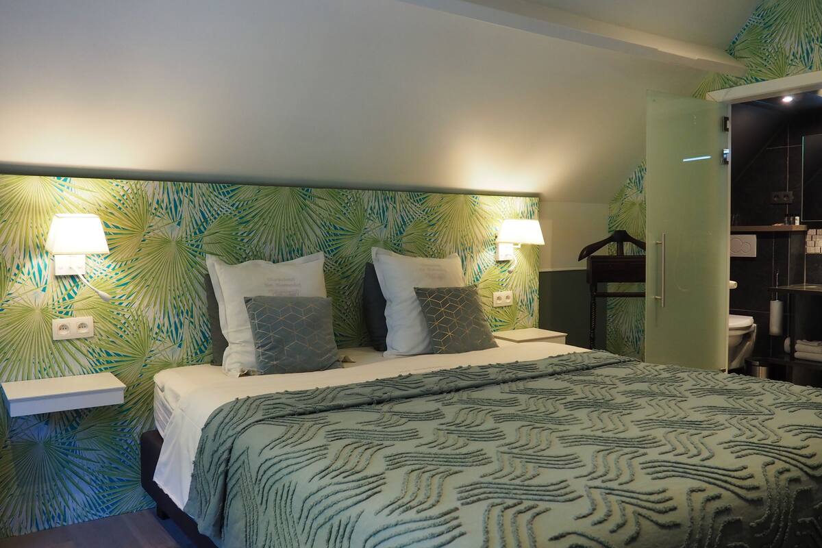 Une chambre d’hôtel comprenant un lit, des tables de chevet, une armoire et une salle de bain.