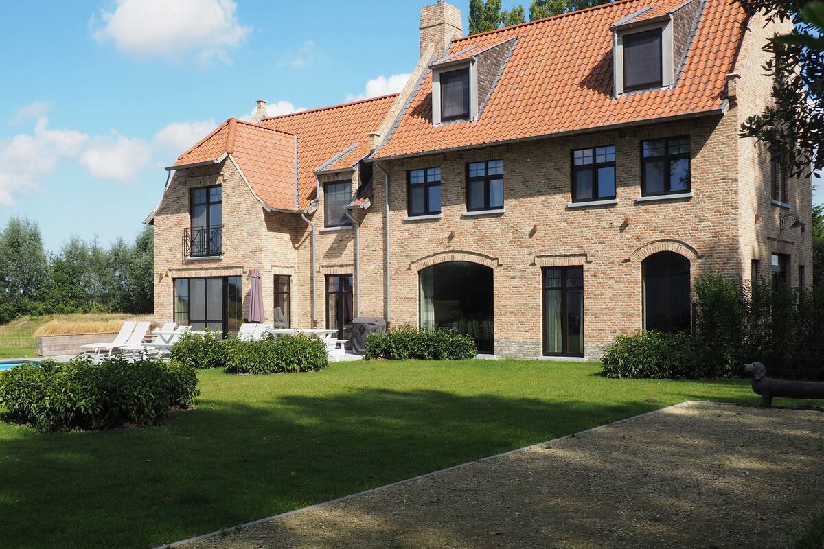 Un bâtiment en pierre à deux étages, doté d’un toit en tuiles, d’une piscine et d’une pelouse bien entretenue.