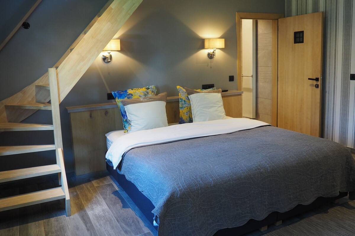 Une chambre à coucher avec un lit, un escalier en bois et une armoire.