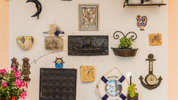 A wall decorated with various items including a crescent moon, a ship, a life preserver, and several potted plants.