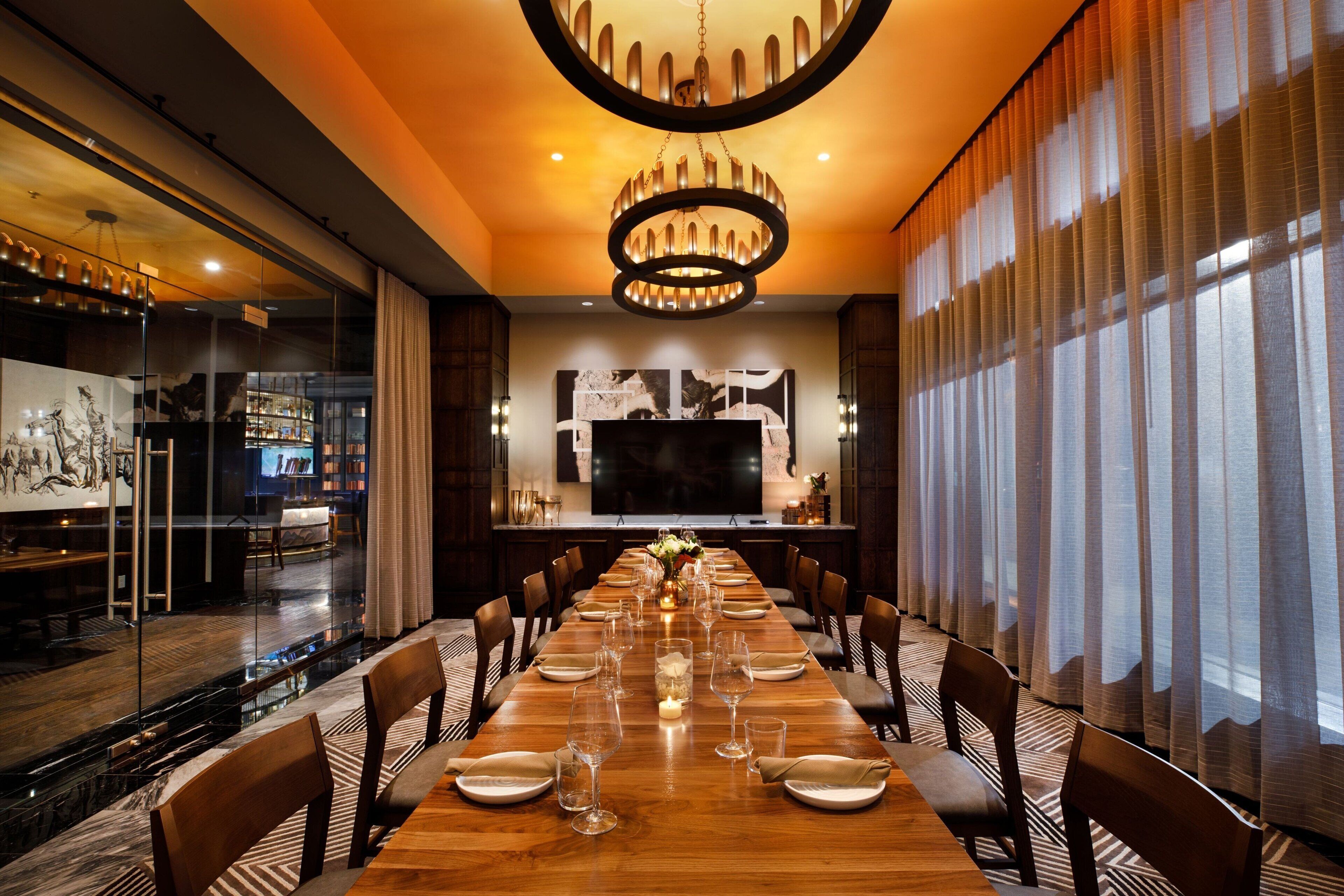 A long dining table set with chairs, a chandelier, and artwork on the walls.
