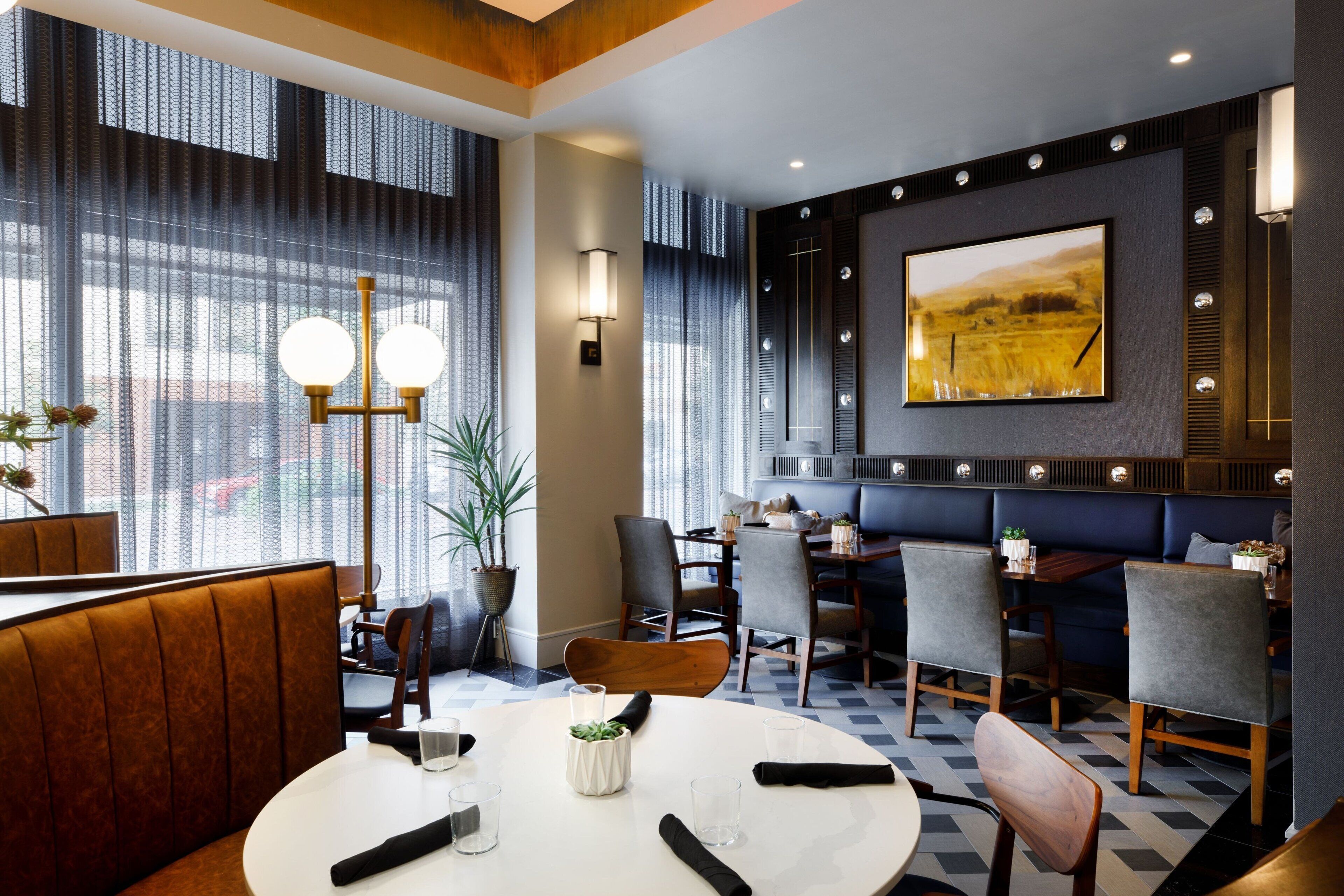 A modern dining area with a round table, chairs, and a booth seating area.