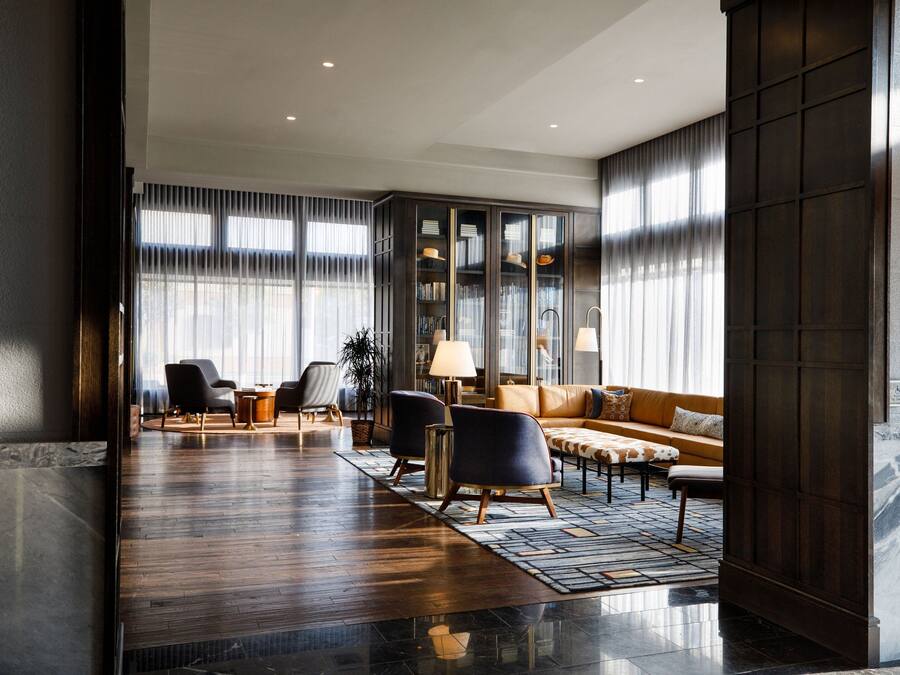 A spacious lobby with a leather sofa, armchairs, a coffee table, and a bookshelf.