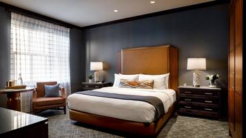 A hotel room with a large bed, two bedside tables with lamps, a chair, and a desk.