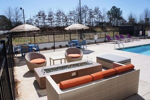 A poolside area with wicker furniture, a fire feature, and umbrellas. - La Quinta Inn & Suites by Wyndham Braselton (Braselton)