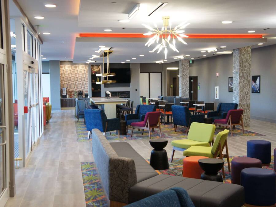 A modern hotel lobby with a variety of seating options, a central bar area, and a patterned wall design.