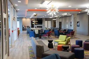 Um lobby de hotel moderno com diversas opções de assento, área de bar central e design de parede estampado.