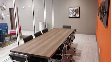 A conference room with a long table, black chairs, and a glass partition.