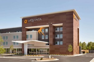 A La Quinta hotel with a modern design, featuring a prominent sun logo and a covered entrance area.