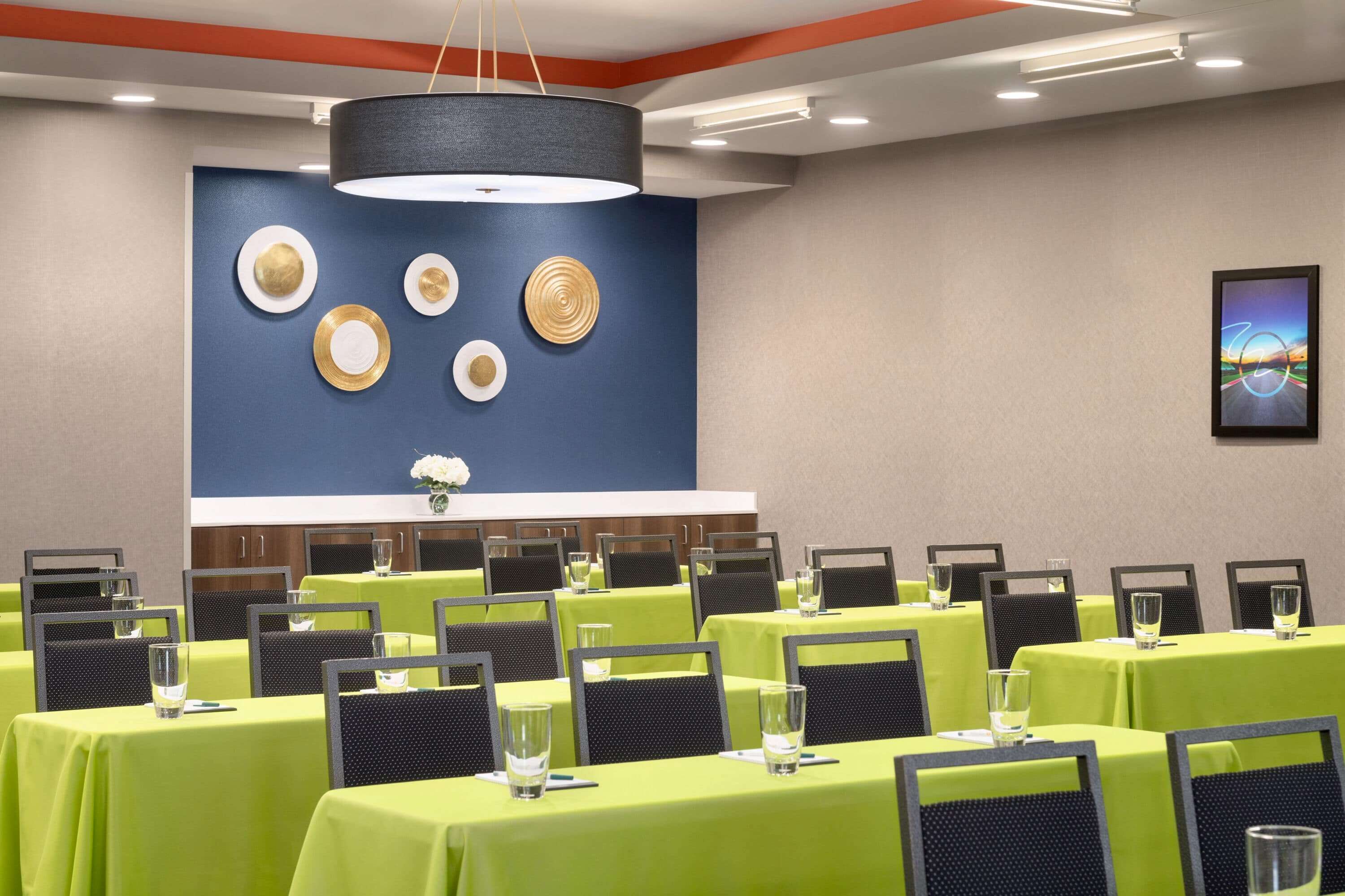 A conference room with tables set for meetings, a large wall-mounted clock, and a modern chandelier.