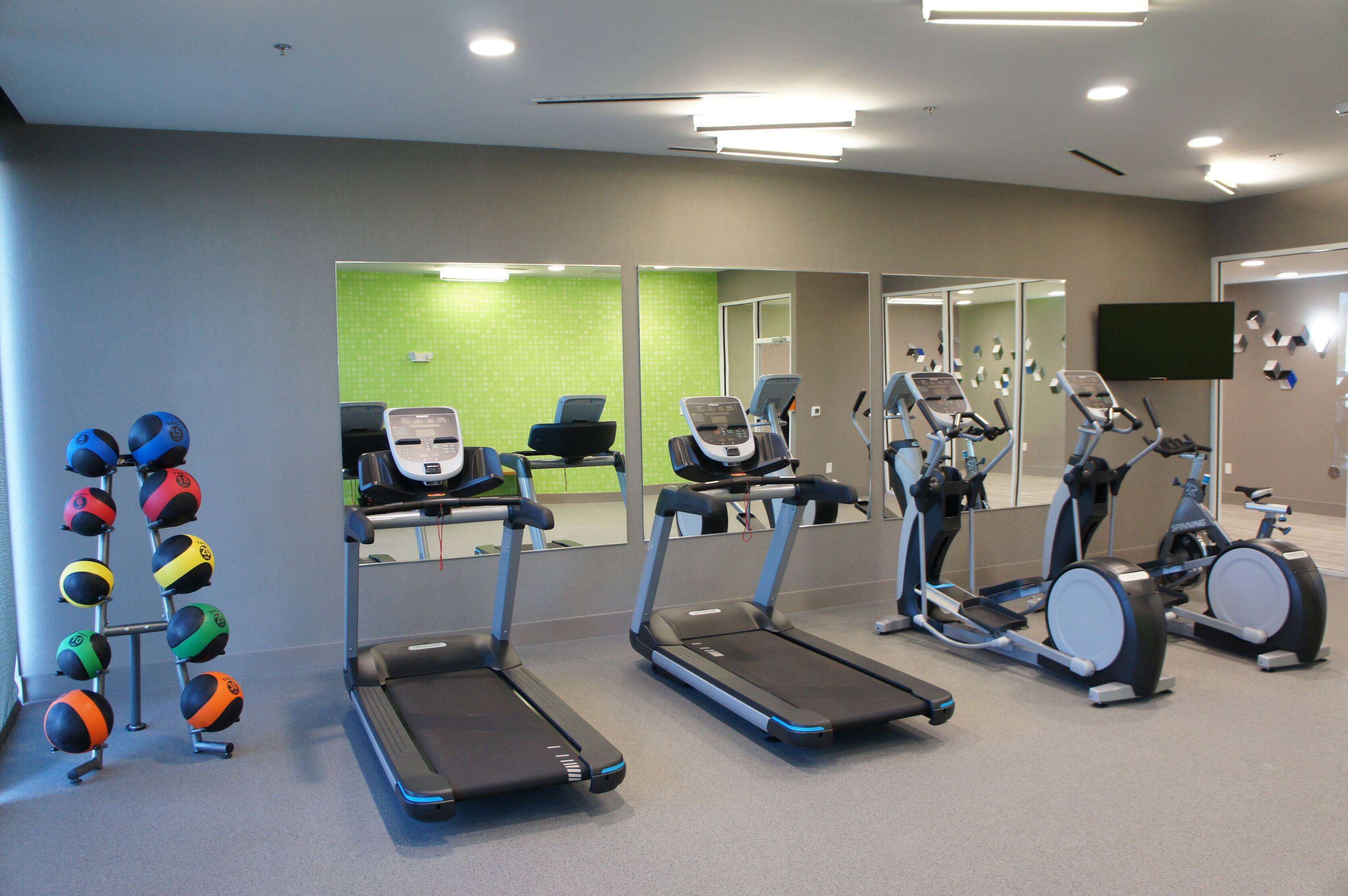 Ett gym med löpband, crosstrainers och ett ställ med färgglada träningsbollar.