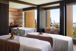 A hotel room with two beds, a marble bathtub, and a city view.