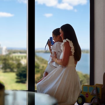 A room with a large window overlooking a cityscape and a body of water.