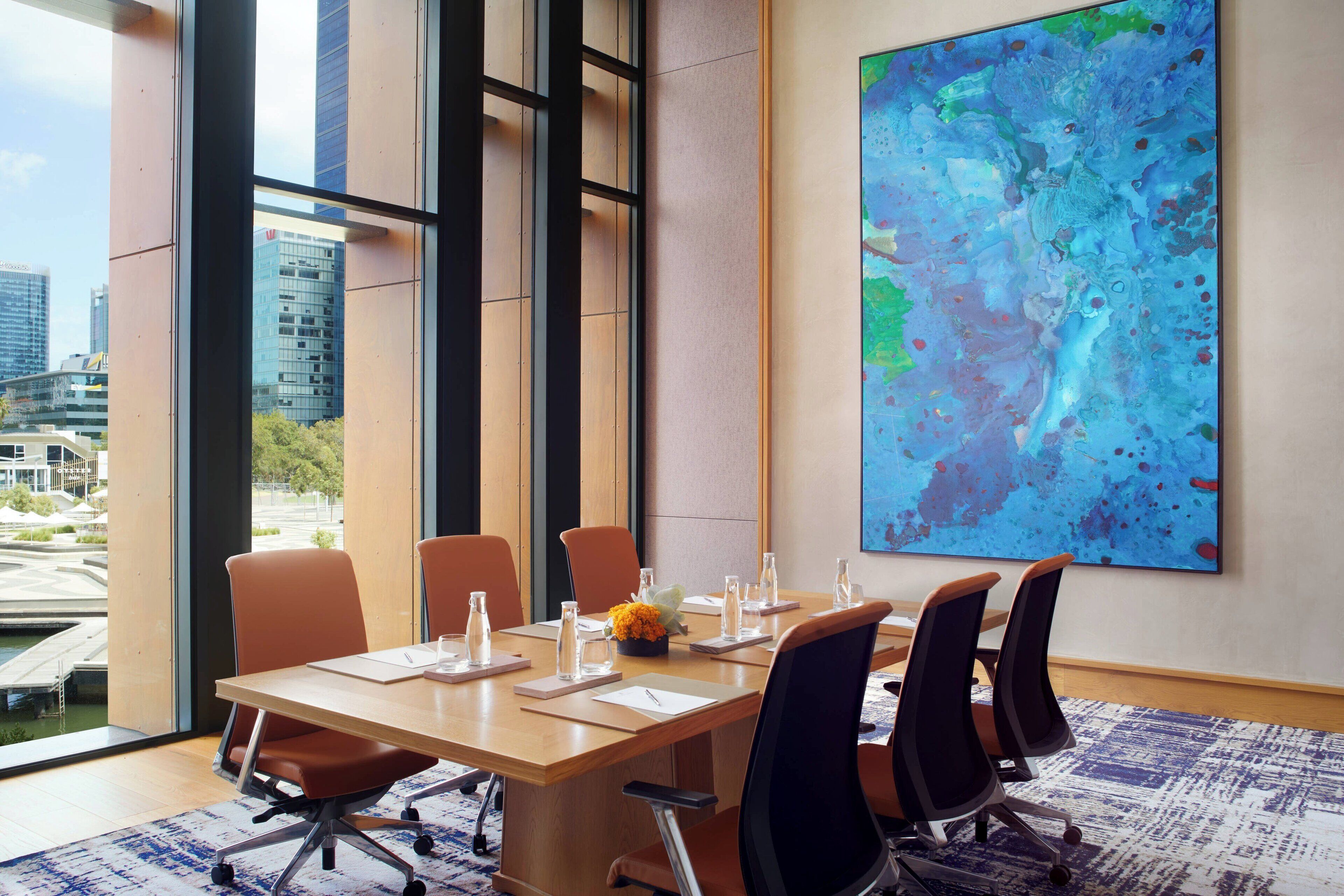 Un salón de conferencias con una gran mesa, seis sillas y un cuadro abstracto de gran tamaño en la pared.
