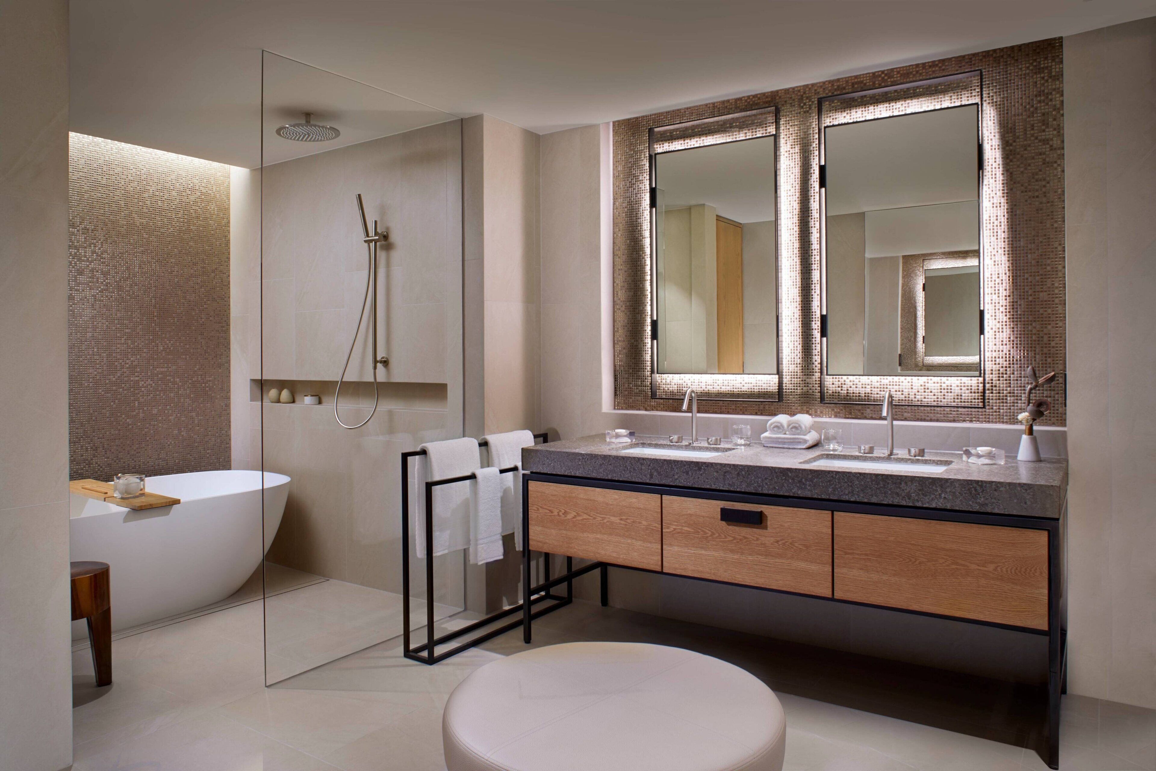 Un baño moderno con una bañera independiente, un espejo grande y un tocador de madera.