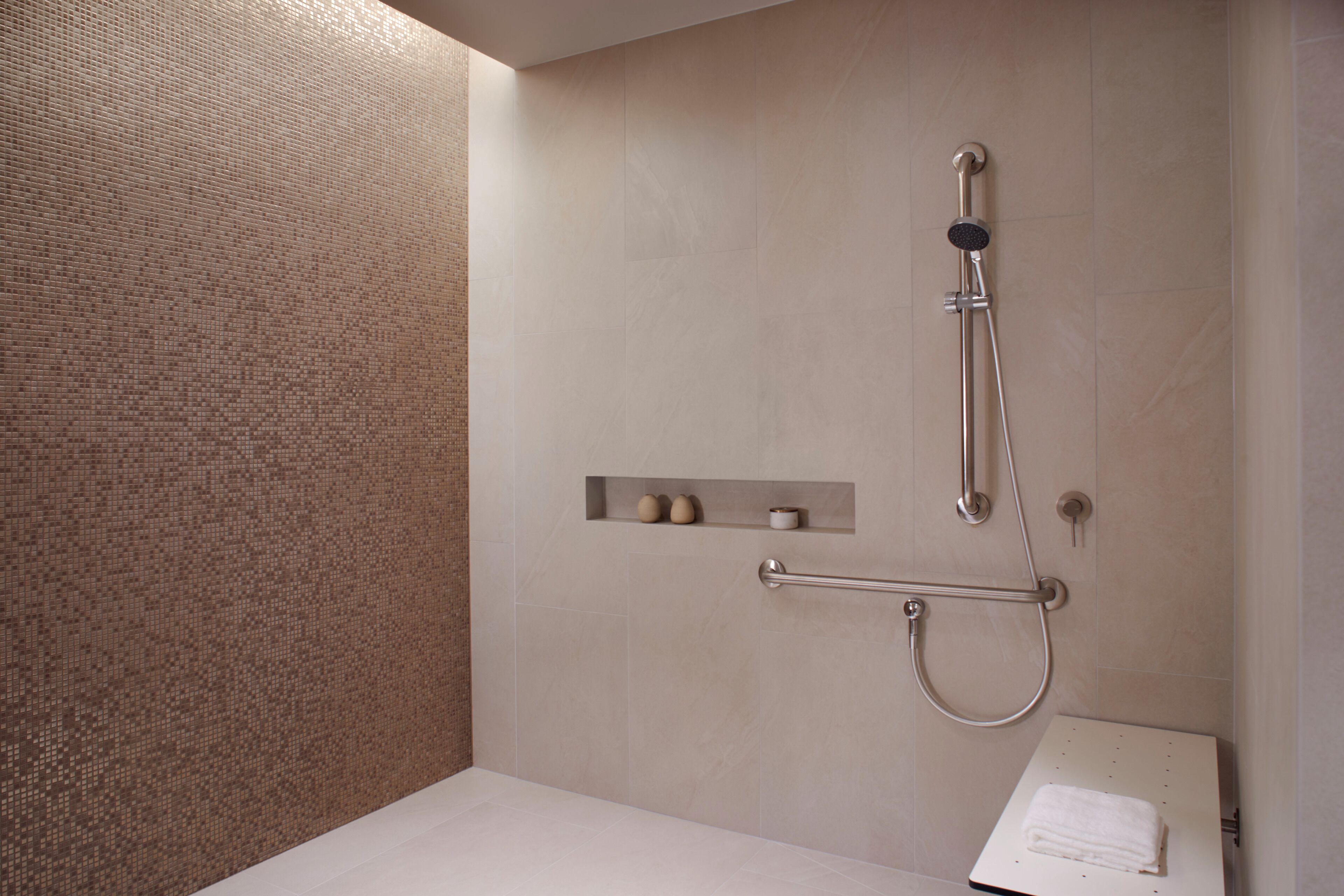A modern bathroom with a shower, a towel rack, and a shelf with toiletries.