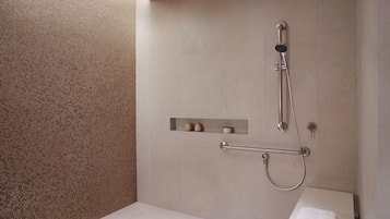 A modern bathroom with a shower, a towel rack, and a shelf with toiletries.