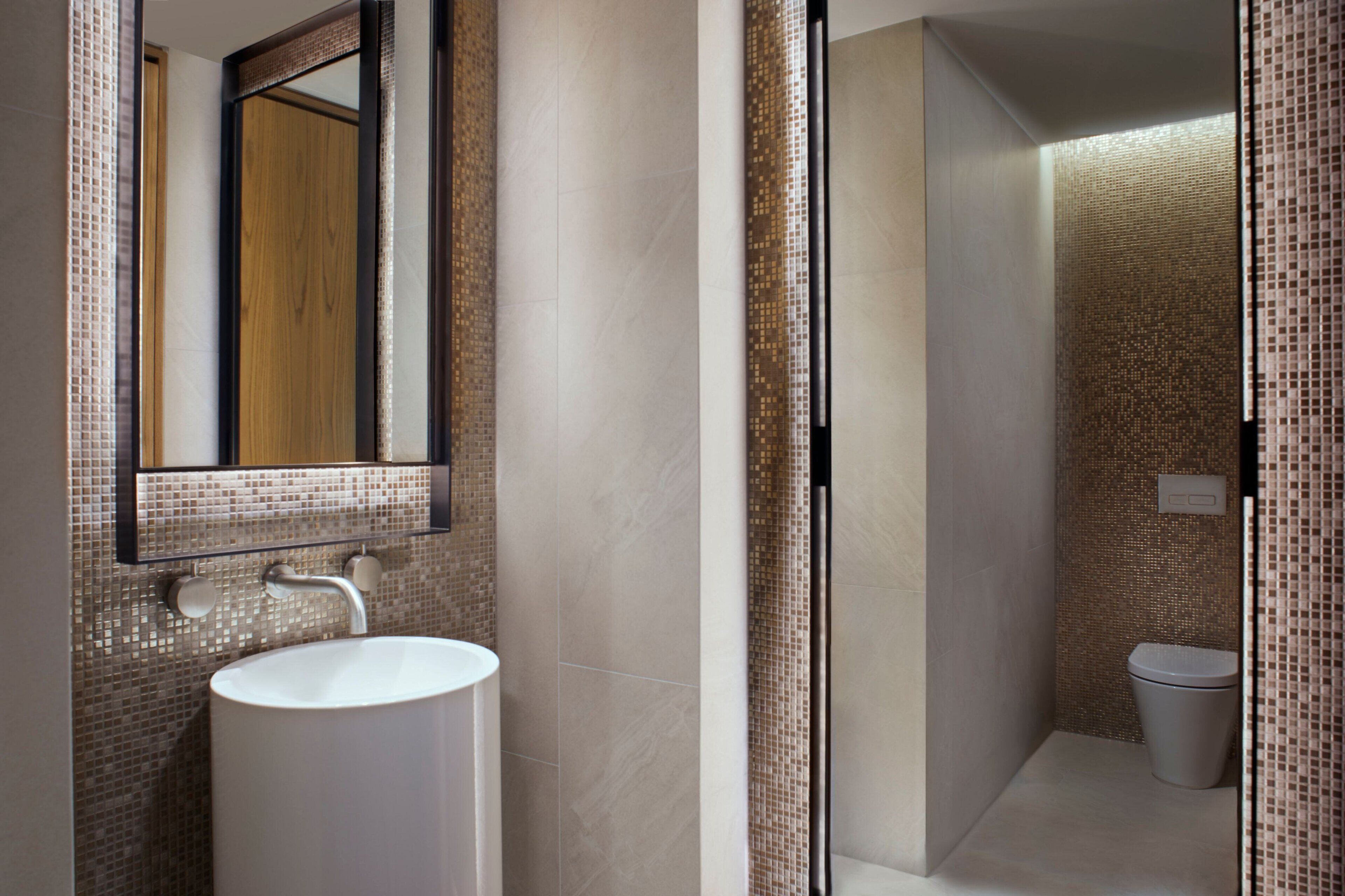 Un baño moderno con un espejo grande, un lavabo y una zona de ducha.