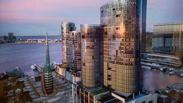 A modern hotel with a glass facade, located near a waterfront.