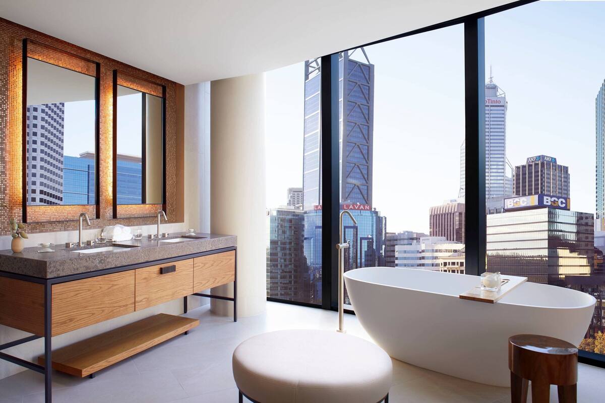 Un baño moderno con una bañera grande, un lavabo doble y un ventanal con vistas a la ciudad.