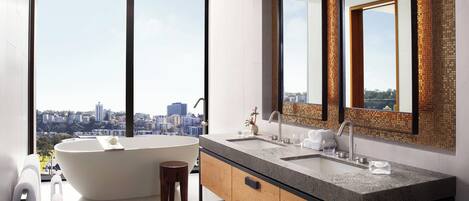A modern bathroom with a freestanding bathtub, a double sink vanity, and large mirrors.