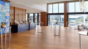 A spacious lobby with a bar area, large windows, and a view of the cityscape.