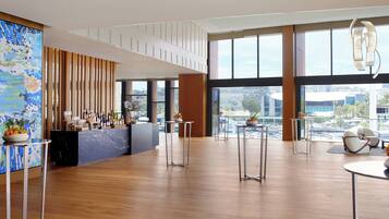A spacious lobby with a bar area, large windows, and a view of the cityscape.