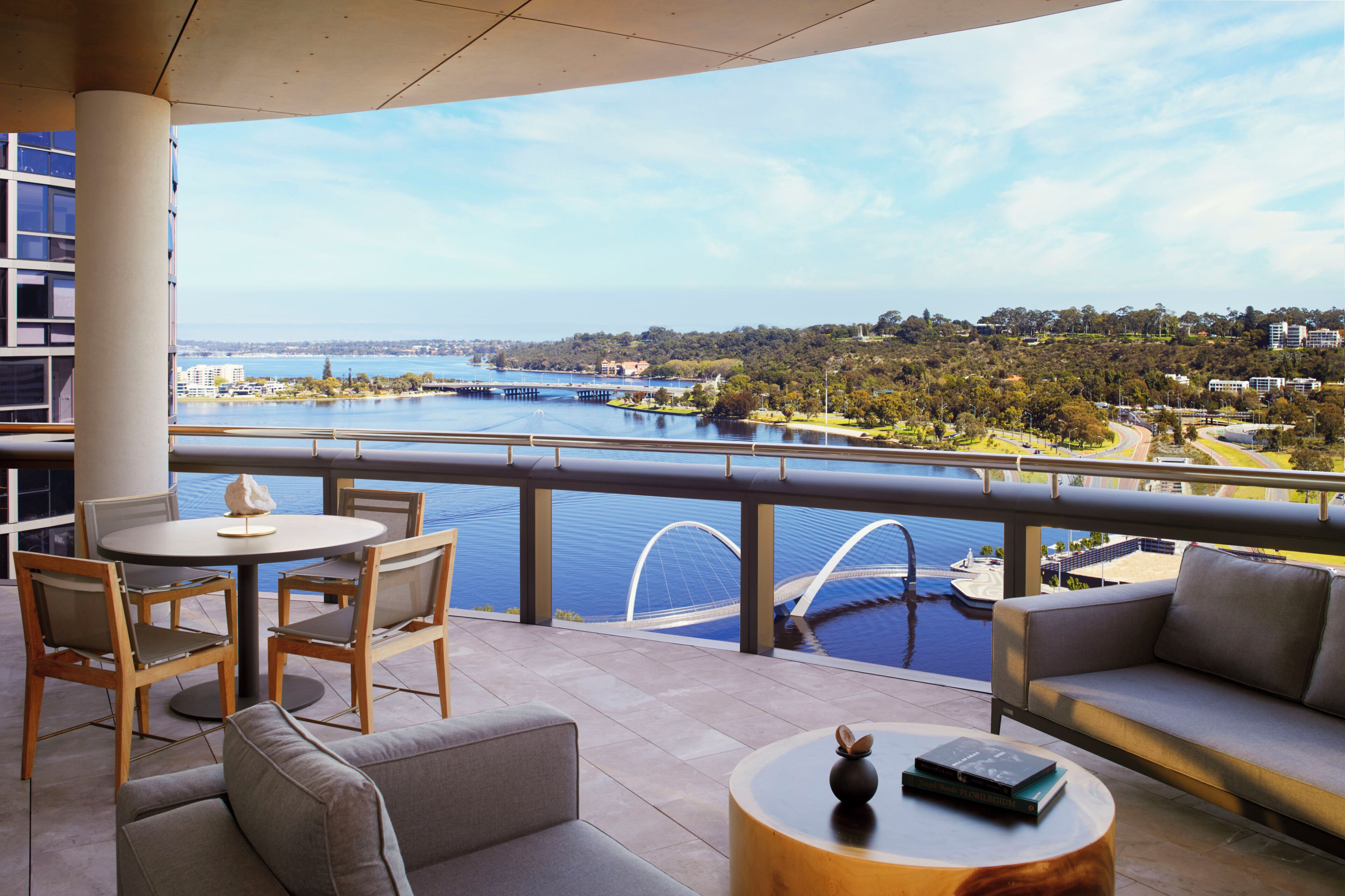 A balcony with a view of a body of water, a dining area with chairs and a table, and a sofa.