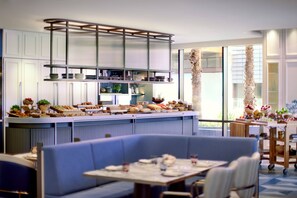 A modern restaurant with a long counter, blue seating, and a view of the outdoors. - The Ritz-Carlton, Perth (Perth)