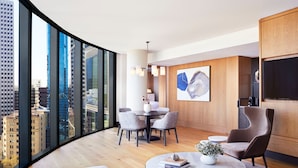 A modern living room with a city view, a dining area, and a flat-screen TV. - The Ritz-Carlton, Perth (Perth)