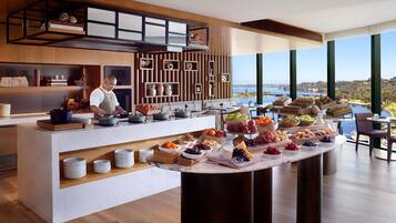 A modern kitchen with a buffet setup, wooden shelves, and a view of the lake.