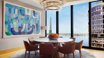 Un espace repas moderne avec une table ronde, six chaises et un grand tableau abstrait accroché au mur.