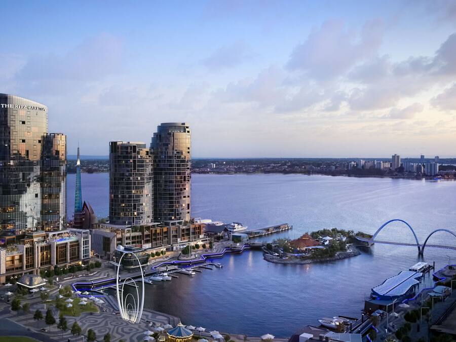 Een hotel aan het water met moderne architectuur, een jachthaven en een opvallende brug.