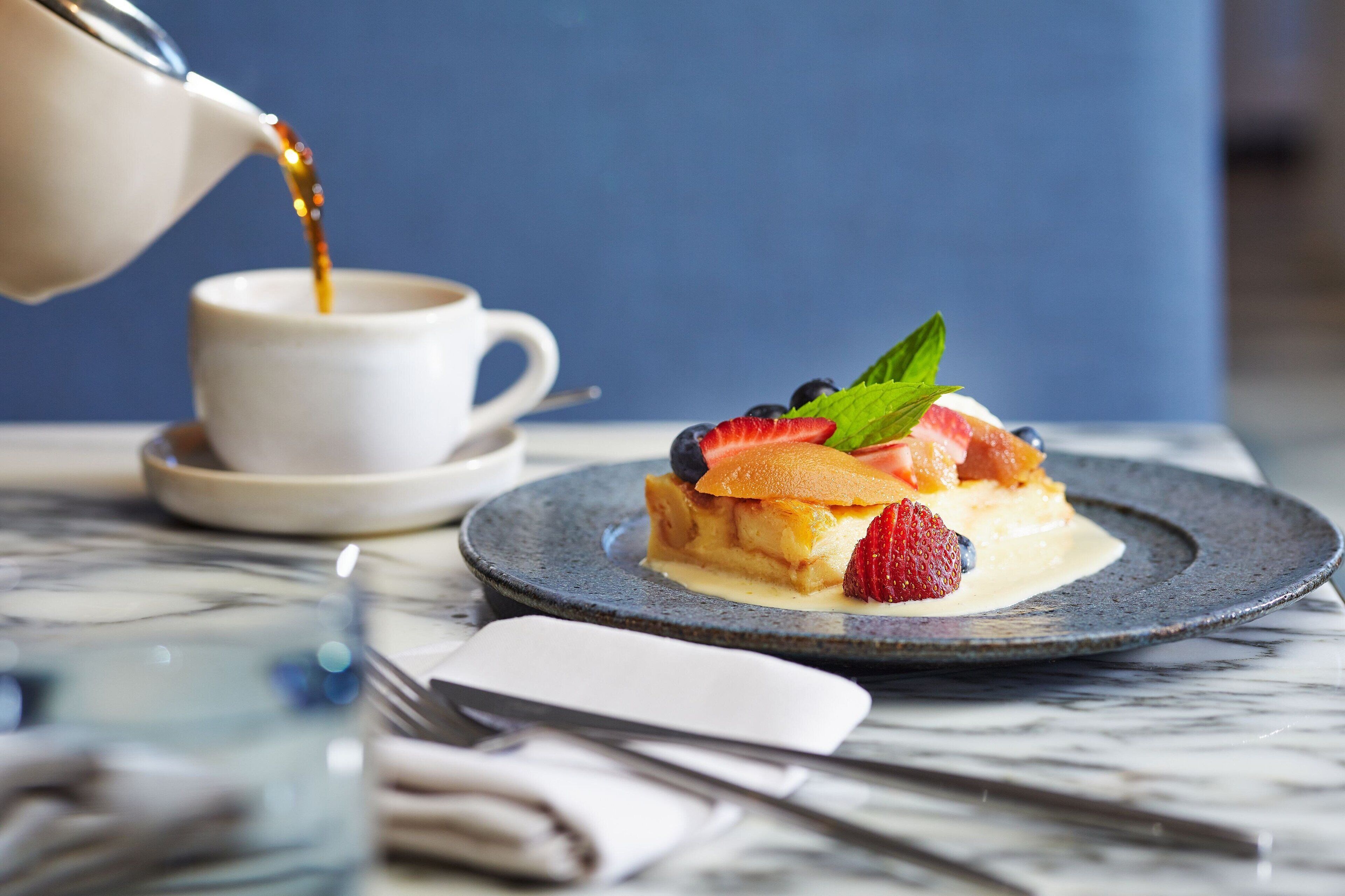 Un postre en un plato con una taza de café al fondo.