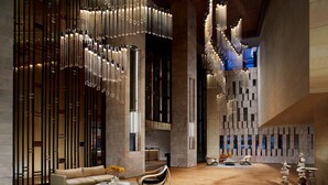 A modern lobby with a wooden floor, a sofa, a round coffee table, and a decorative chair.