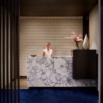 A reception desk with a marble top, a decorative vase, and a patterned backdrop.