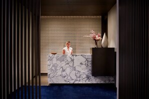 A reception desk with a marble top, a decorative vase, and a patterned backdrop.