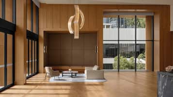 A spacious room with a wooden floor, a seating area with two sofas and a coffee table, a large window with a view, and a modern light fixture.