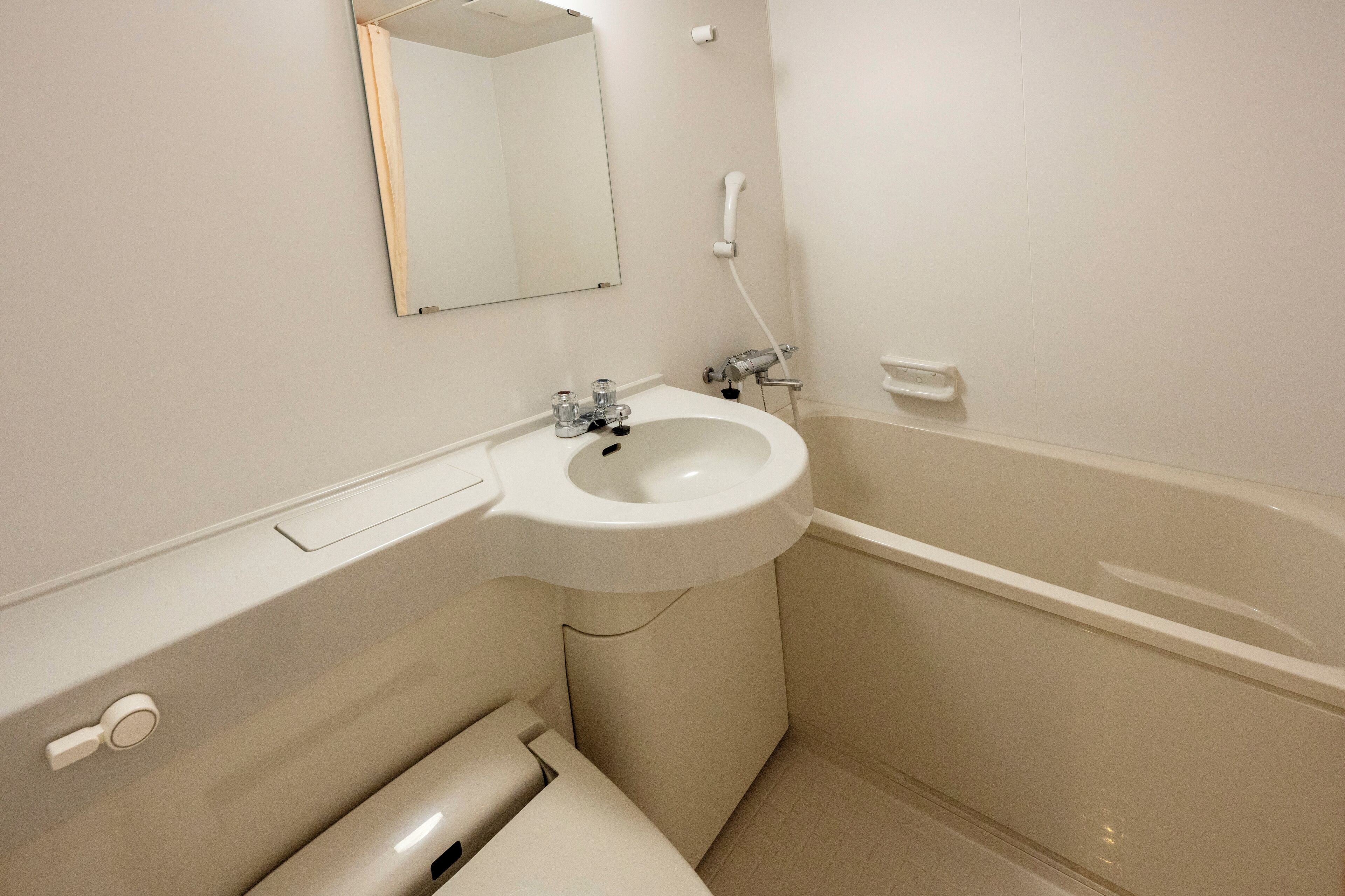 A bathroom with a sink, mirror, and bathtub.