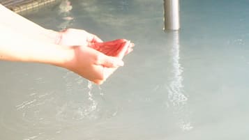 A hand holding a red object over a pool.