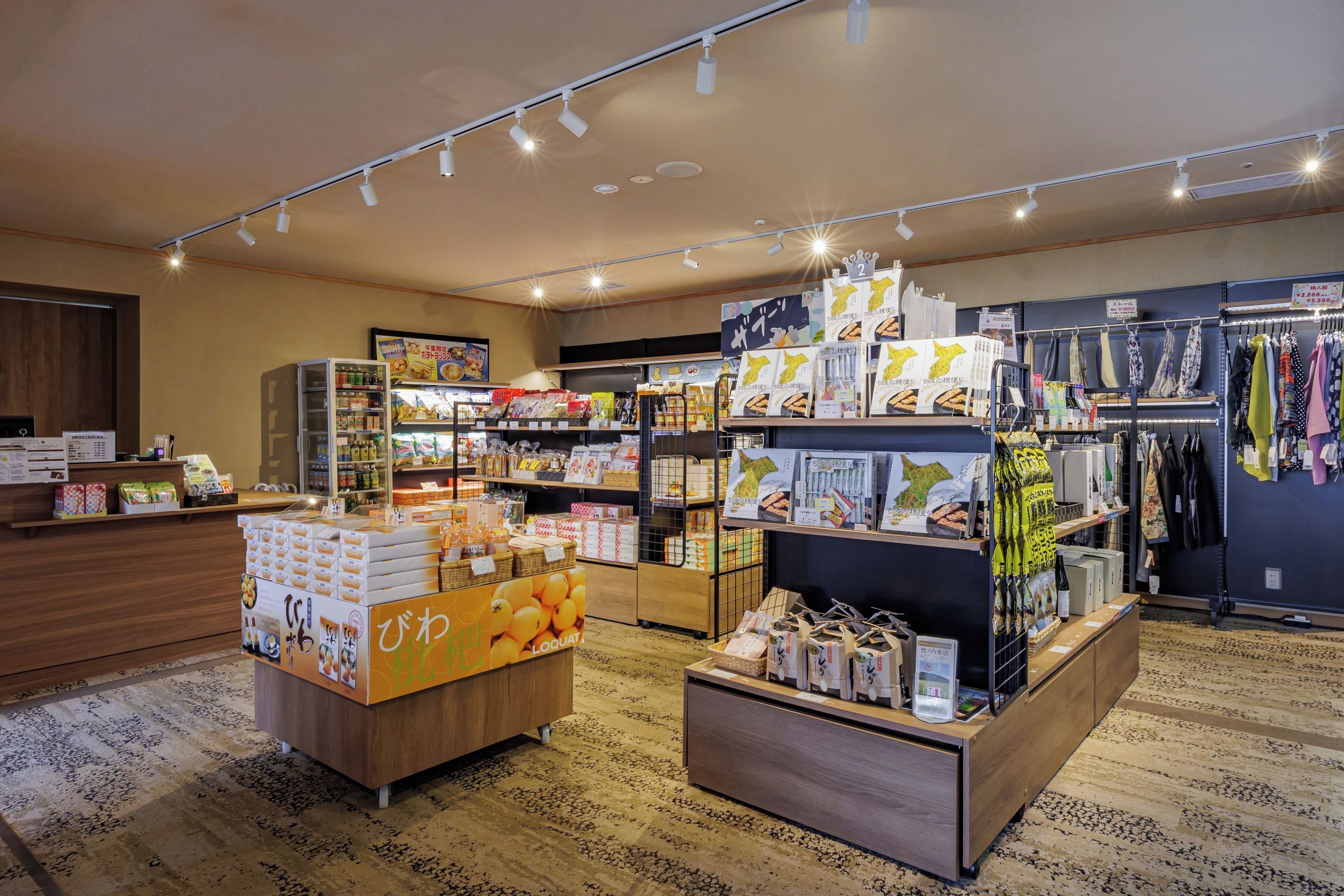 A store interior with shelves stocked with various products, a display counter with boxes, and a patterned carpet.